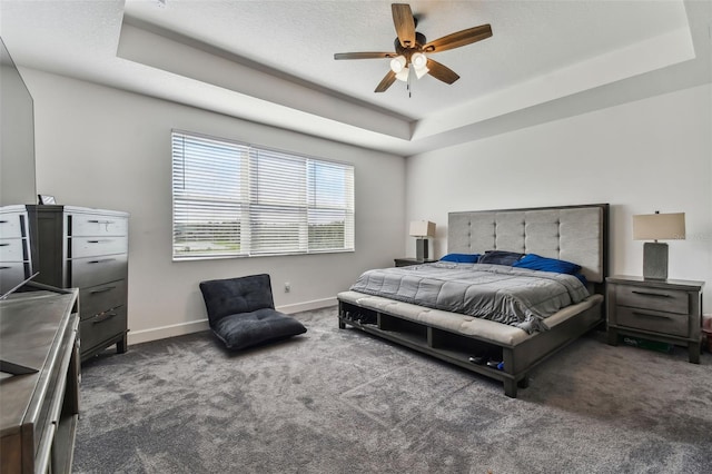 carpeted bedroom with ceiling fan and a raised ceiling