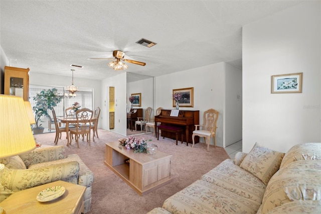 carpeted living room with a textured ceiling and ceiling fan with notable chandelier