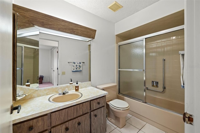 full bathroom featuring combined bath / shower with glass door, a textured ceiling, toilet, vanity, and tile patterned floors