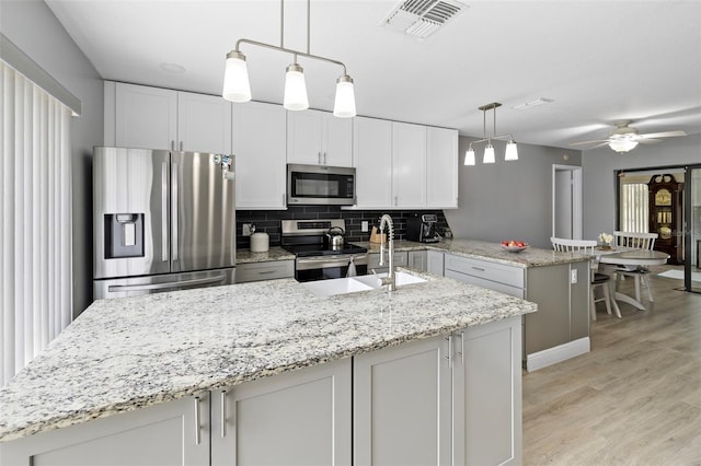 kitchen with white cabinetry, stainless steel appliances, kitchen peninsula, and pendant lighting