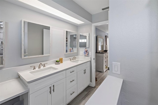 full bath with double vanity, wood finished floors, and a sink