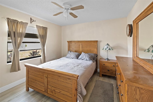 bedroom with ceiling fan, a textured ceiling, and light hardwood / wood-style flooring