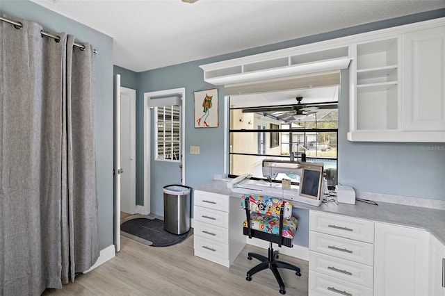 office space featuring light wood-style flooring, a textured ceiling, baseboards, and a ceiling fan