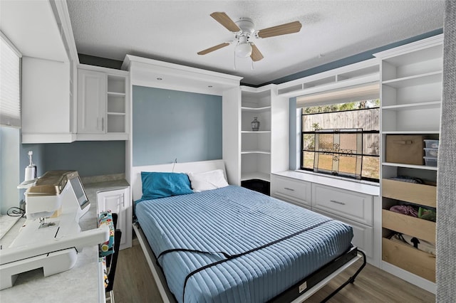 bedroom with a textured ceiling, wood finished floors, and a ceiling fan