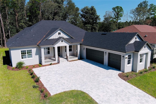 view of front of house featuring a front lawn, covered porch, and a garage