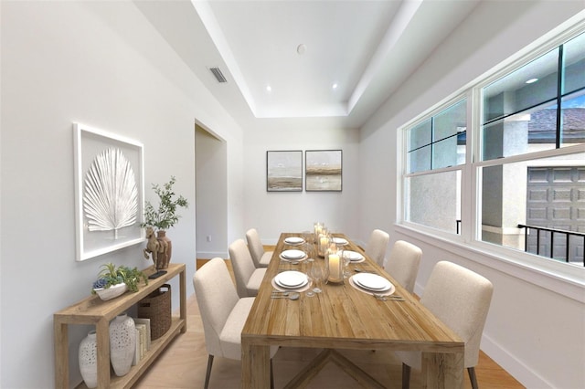 dining room with a tray ceiling and light wood-type flooring