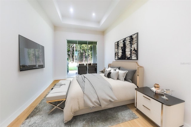 bedroom featuring light hardwood / wood-style floors and a tray ceiling