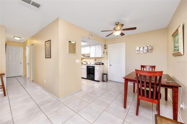 kitchen featuring black dishwasher, tasteful backsplash, light tile patterned flooring, ceiling fan, and white cabinets