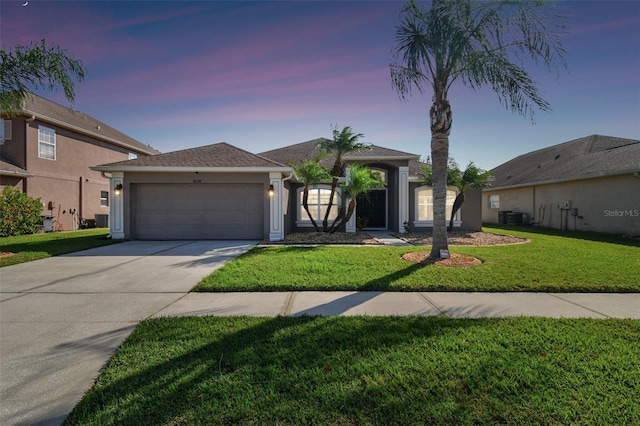 view of front of home featuring a yard, cooling unit, and a garage