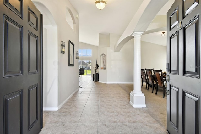 foyer entrance with lofted ceiling, ornate columns, and light tile patterned floors