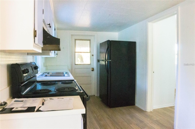 kitchen with black refrigerator, white cabinetry, and light wood-type flooring