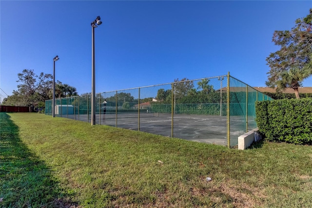 view of tennis court with a yard