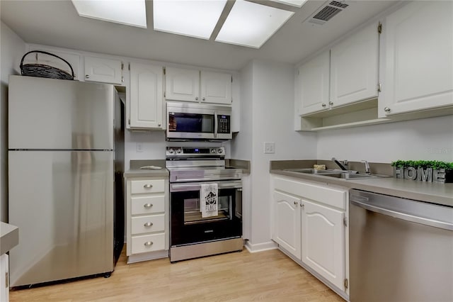 kitchen featuring light wood-type flooring, appliances with stainless steel finishes, sink, and white cabinets