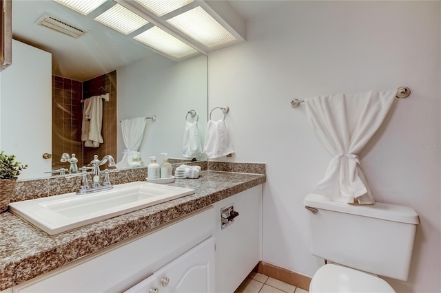 bathroom with toilet, vanity, and tile patterned floors