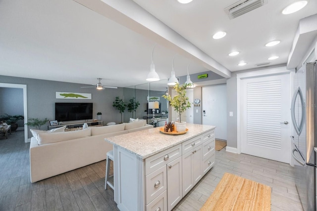 kitchen featuring white cabinetry, a kitchen bar, pendant lighting, light hardwood / wood-style floors, and a center island