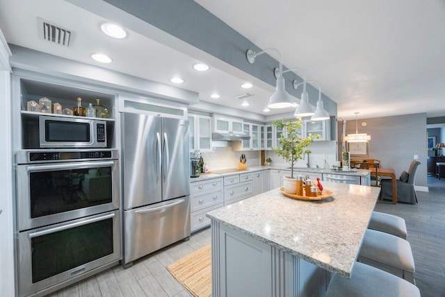 kitchen featuring a breakfast bar, a center island, white cabinetry, appliances with stainless steel finishes, and light hardwood / wood-style floors