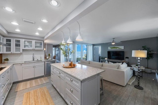 kitchen featuring a kitchen island, dishwasher, hanging light fixtures, white cabinetry, and light hardwood / wood-style floors