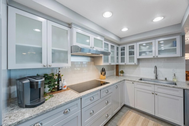 kitchen with sink, light stone countertops, decorative backsplash, and black electric cooktop