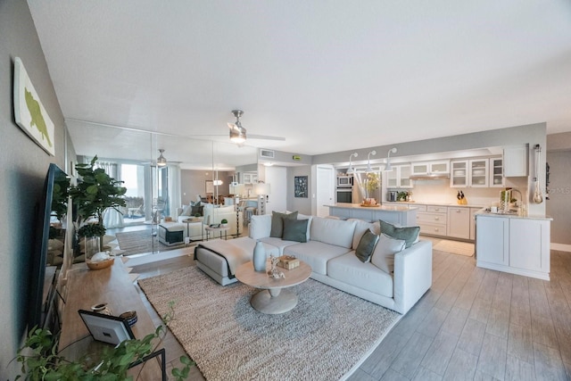 living room with sink, light hardwood / wood-style flooring, and ceiling fan