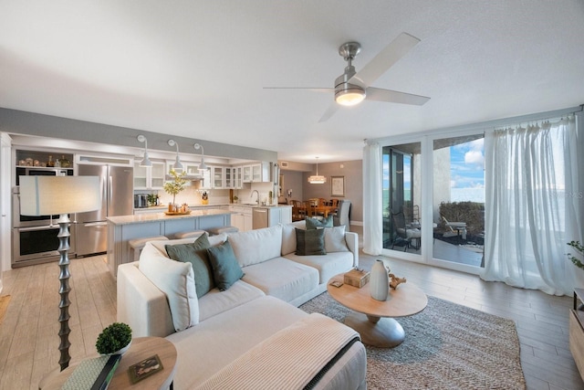 living room featuring sink, light hardwood / wood-style floors, and ceiling fan