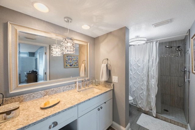 bathroom with wood-type flooring, a textured ceiling, a shower with shower curtain, toilet, and vanity