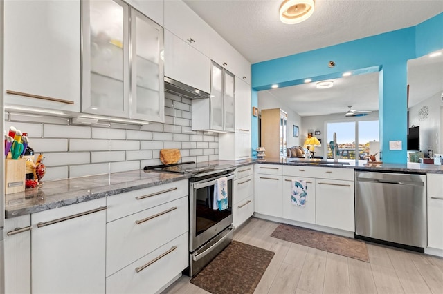 kitchen featuring backsplash, stone counters, white cabinets, sink, and appliances with stainless steel finishes