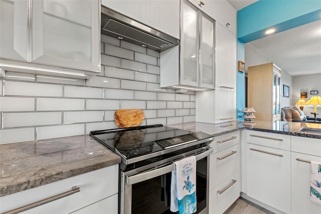 kitchen with backsplash, electric stove, white cabinets, and dark stone counters