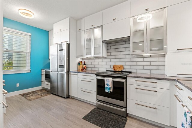 kitchen with white cabinets, tasteful backsplash, appliances with stainless steel finishes, and light hardwood / wood-style flooring