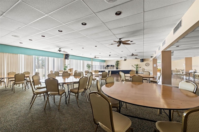 dining room with a paneled ceiling, ceiling fan, and carpet