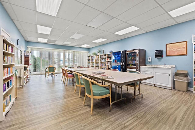 dining space featuring a drop ceiling and light wood-type flooring