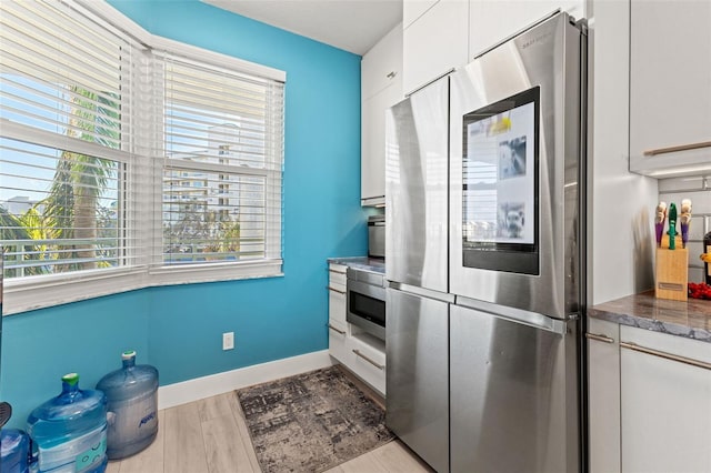 kitchen featuring white cabinetry, stainless steel fridge, light hardwood / wood-style flooring, and a healthy amount of sunlight