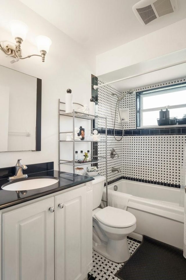 full bathroom with tile patterned floors, vanity, tiled shower / bath combo, and toilet