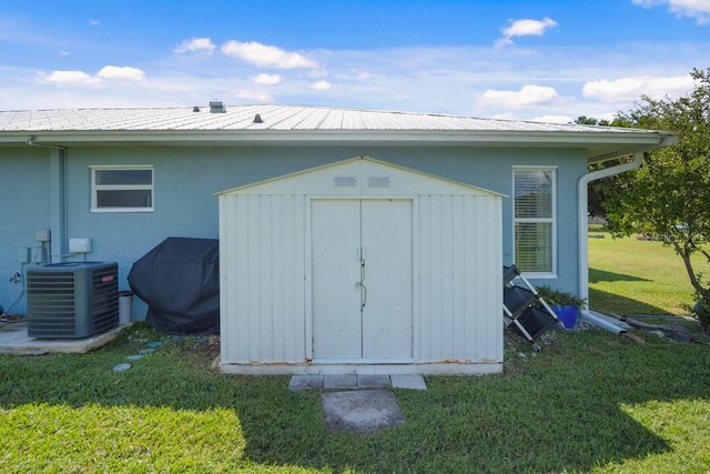 view of outdoor structure featuring central AC unit and a yard