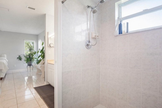 bathroom featuring tile patterned flooring, a tile shower, and vanity