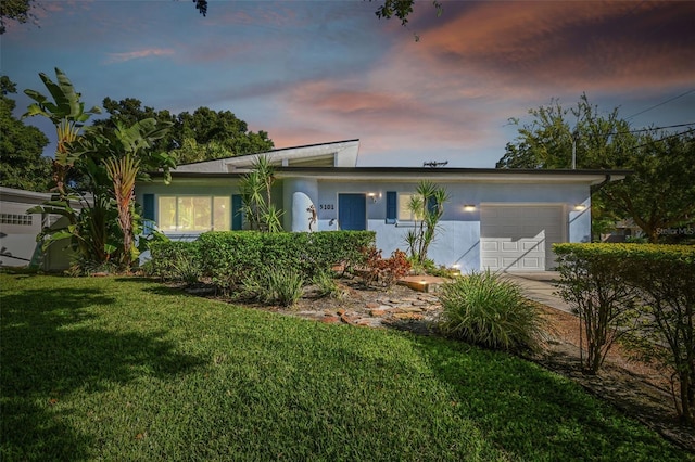 ranch-style home with a garage and a yard