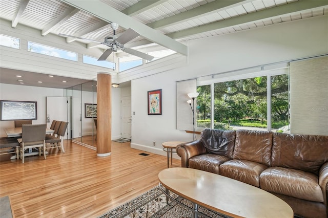 living room featuring high vaulted ceiling, light hardwood / wood-style floors, beamed ceiling, and ceiling fan