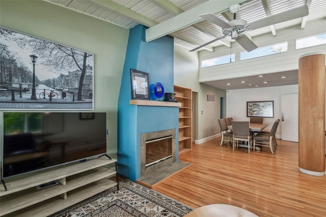 living room with hardwood / wood-style flooring, ceiling fan, plenty of natural light, and a towering ceiling