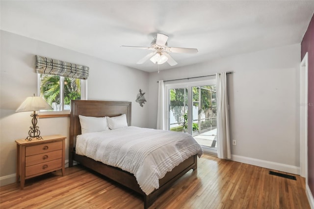 bedroom featuring access to exterior, wood-type flooring, multiple windows, and ceiling fan