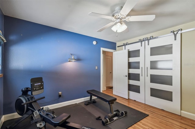 workout room with hardwood / wood-style floors, a barn door, and ceiling fan