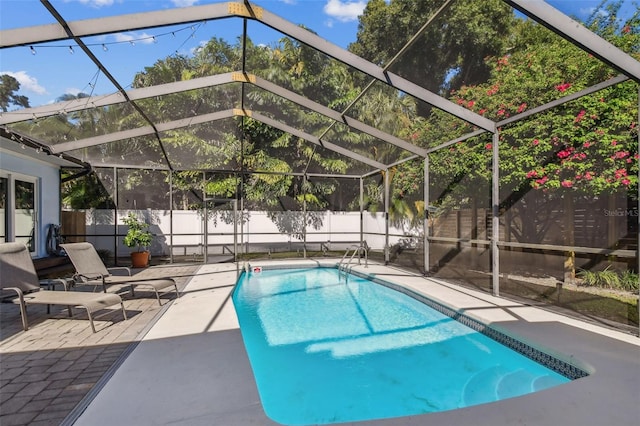 view of pool with glass enclosure and a patio area