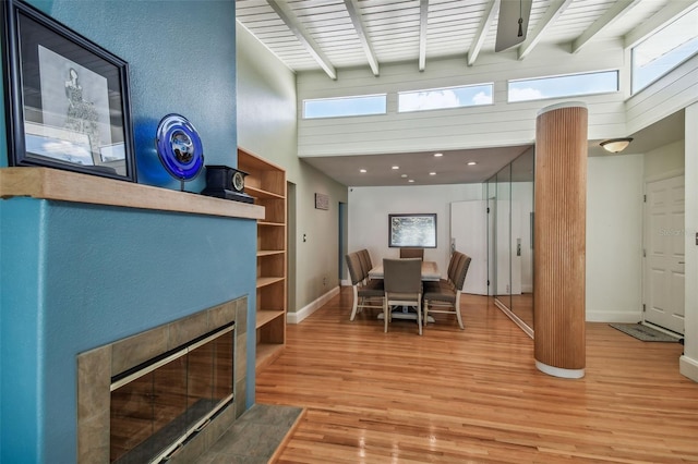 dining area with hardwood / wood-style floors, a towering ceiling, and beam ceiling