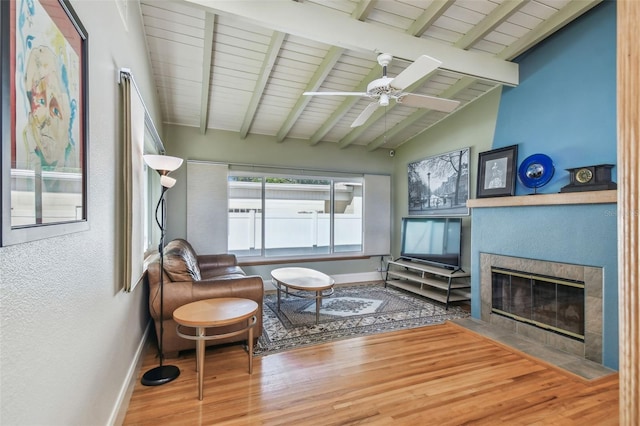 interior space featuring lofted ceiling with beams, a tiled fireplace, wood ceiling, and ceiling fan