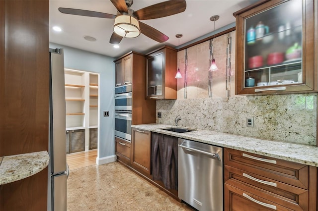 kitchen with pendant lighting, stainless steel appliances, sink, and light stone countertops