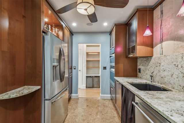 kitchen featuring sink, appliances with stainless steel finishes, light stone countertops, ceiling fan, and pendant lighting