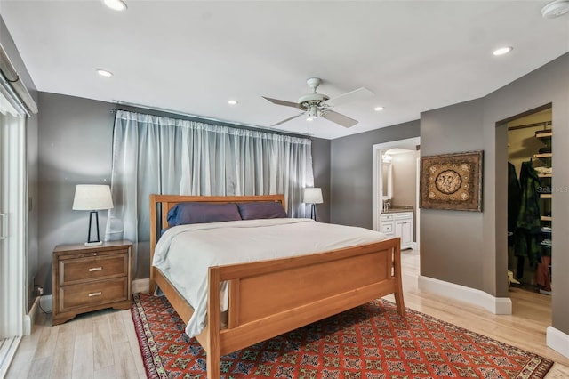 bedroom with light hardwood / wood-style floors, ceiling fan, and connected bathroom