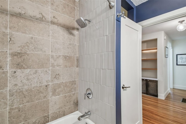 bathroom with hardwood / wood-style floors and tiled shower / bath