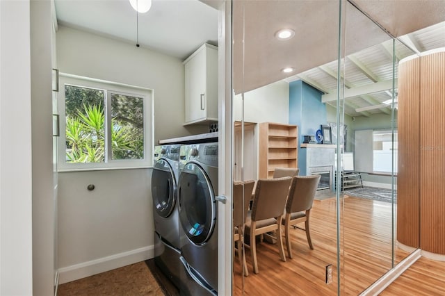 laundry area with cabinets, washing machine and clothes dryer, and light hardwood / wood-style floors