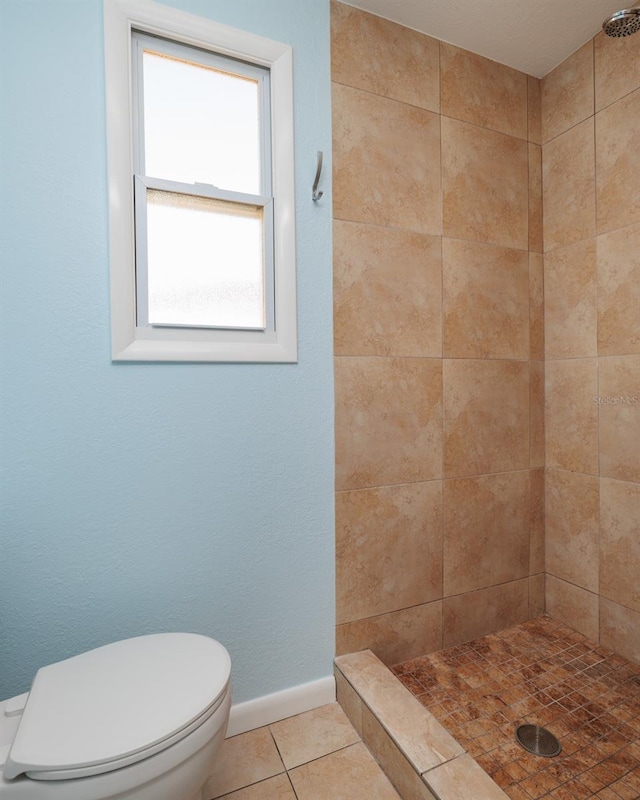 bathroom featuring a tile shower, toilet, and tile patterned flooring