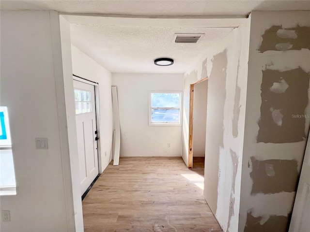 corridor featuring light hardwood / wood-style flooring and a textured ceiling