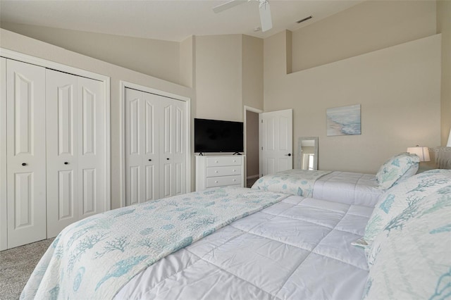 carpeted bedroom with multiple closets, lofted ceiling, and ceiling fan